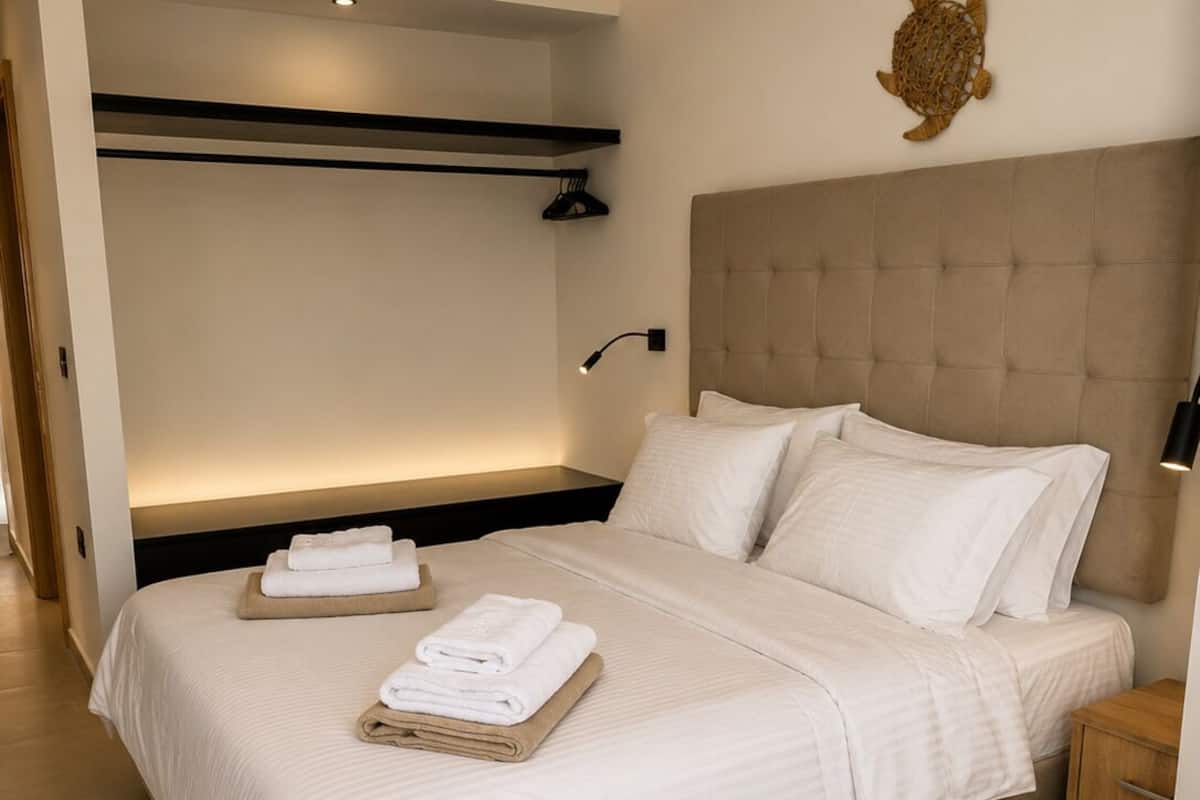 Una habitación de hotel moderna con una cama grande, cabecera, estante en la pared, lámpara de noche y un adorno mural.