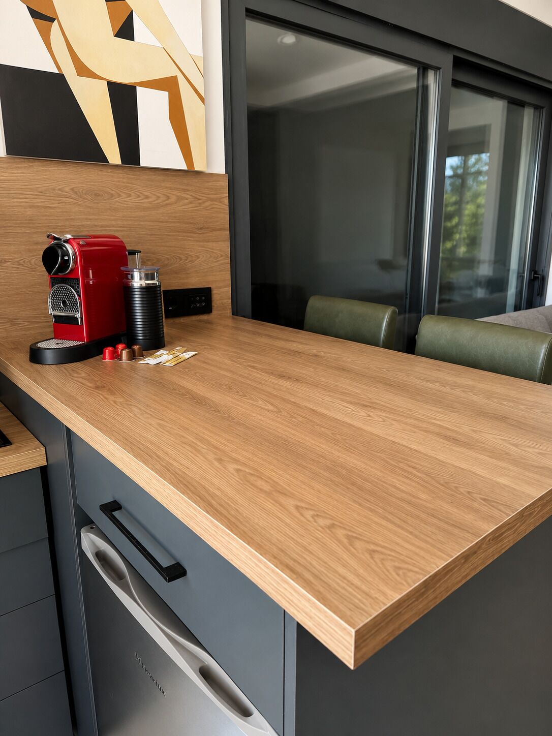 Una cocina con cafetera, molinillo de café y un mueble con cajones.