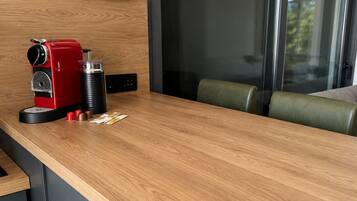 Una cocina con cafetera, molinillo de café y un mueble con cajones.