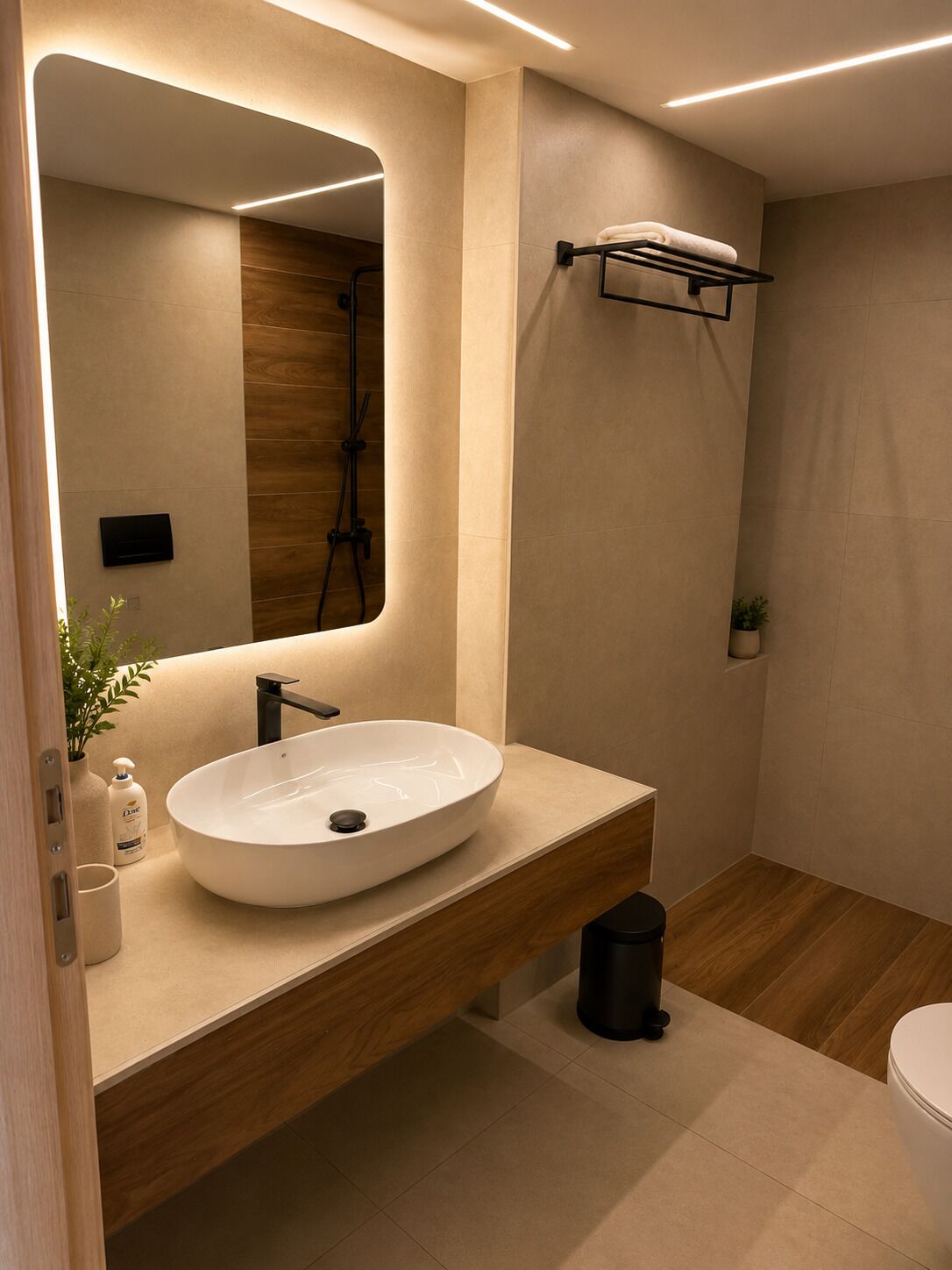 A modern bathroom with a large oval sink, a mirror, a towel rack, and a shower area.
