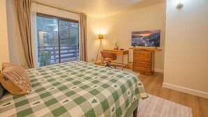 Una camera da letto con un letto, una scrivania, una sedia, una cassettiera, una finestra con tende e un quadro appeso al muro.