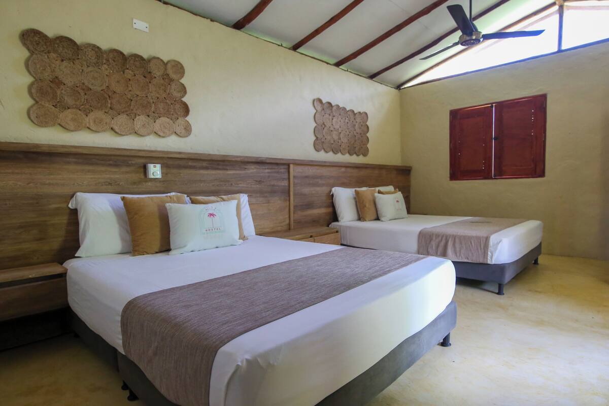 A hotel room with two beds, wooden headboards, a ceiling fan, and a wall decoration.
