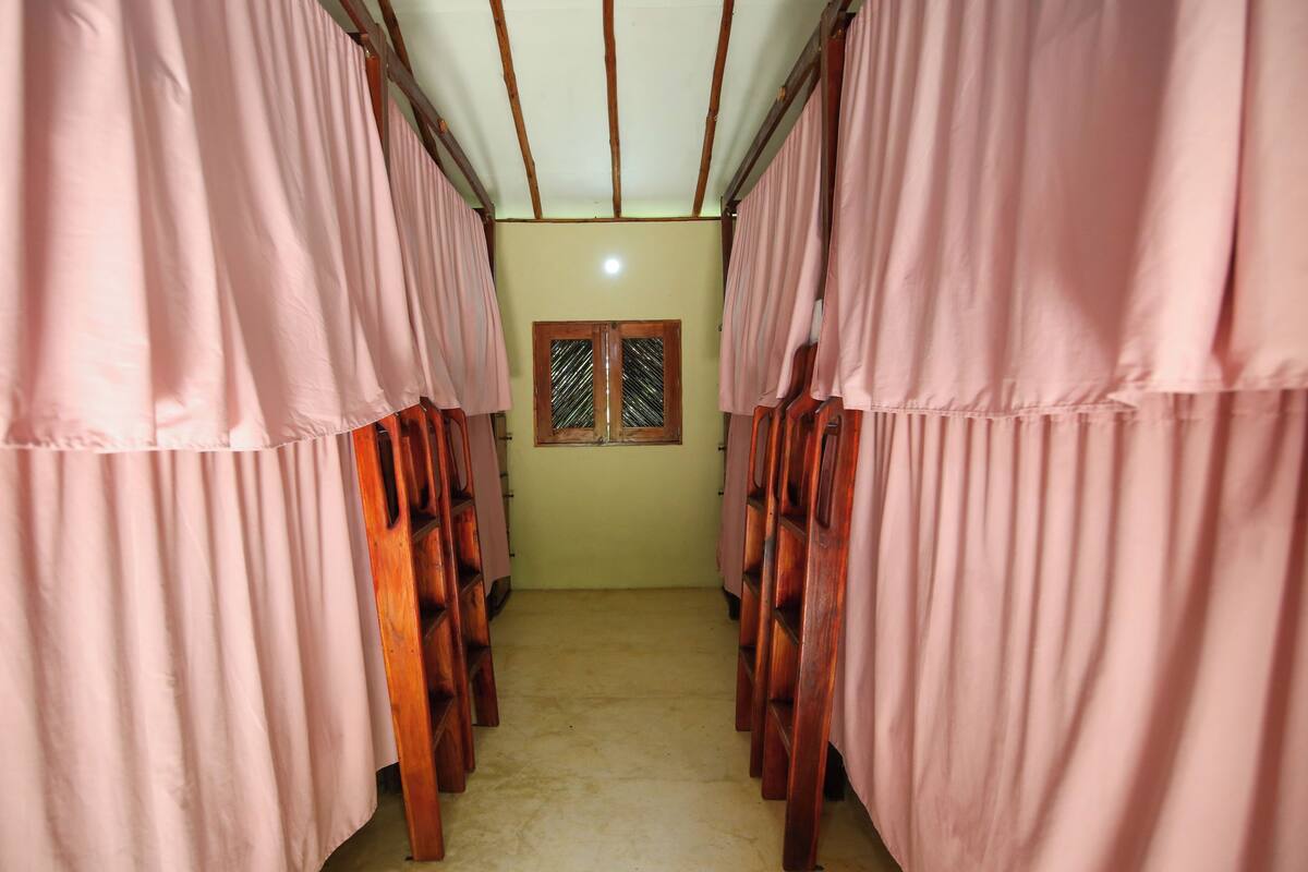 A corridor with bunk beds, a window with a wooden frame, and a plain wall.