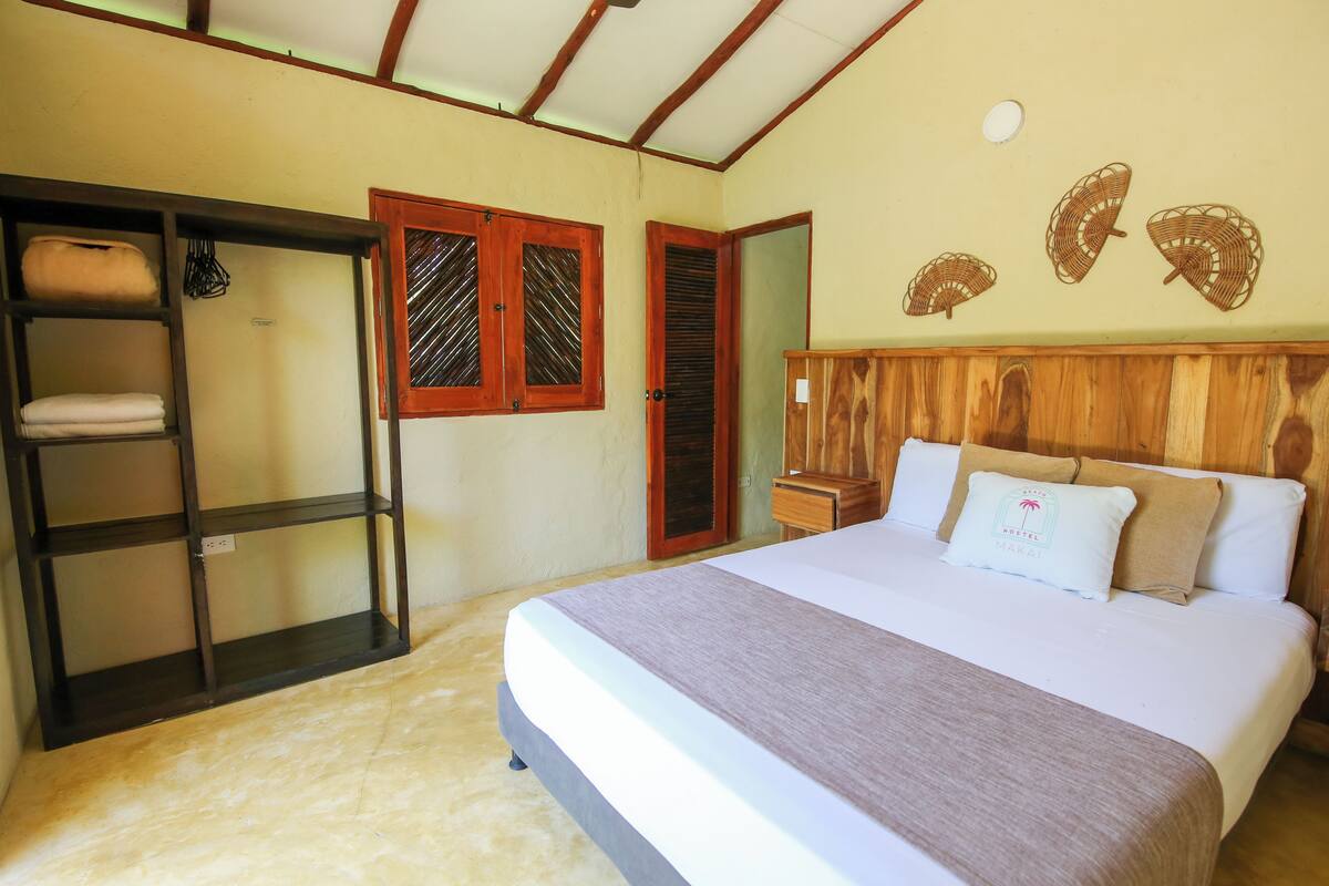 A bedroom with a bed, wooden headboard, a wardrobe, and a shelf unit.
