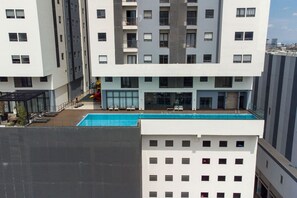 A multi-story building with a rooftop swimming pool, balconies, and a children's play area.