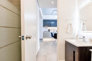 A modern bathroom with a large mirror, a sink, and a door leading to a kitchen area with a dining table and chairs. - 1 Queen, 1 Sofa Bed, Wifi, Gym, Pool - 4 people (Monterrey)