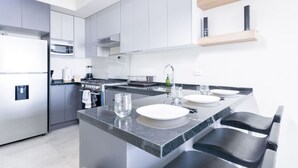 Une cuisine moderne dotée d’un îlot central, d’appareils électroménagers en acier inoxydable et d’un design minimaliste.
