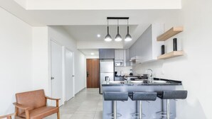 Une cuisine moderne dotée d’un îlot central, de tabourets de bar et de luminaires suspendus.