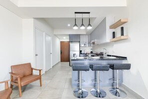 A modern kitchen with a central island, bar stools, and pendant lighting.