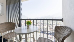 A balcony with wicker chairs, a small round table, and a potted plant. - 1 Queen, 2 Sofa Beds, WiFi, Gym, Pool – Sleeps 5 (Monterrey)