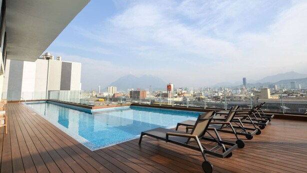 A rooftop pool with lounge chairs and a cityscape view. - 1 Queen, 2 Sofa Beds, WiFi, Gym, Pool – Sleeps 5 (Monterrey)