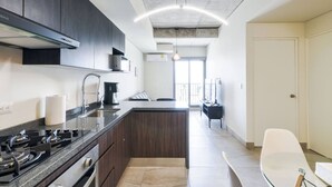 A modern kitchen with dark cabinets, a gas stove, and a central island. - 1 Queen, 2 Sofa Beds, WiFi, Gym, Pool – Sleeps 5 (Monterrey)