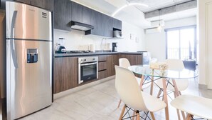 A modern kitchen with a stainless steel refrigerator, built-in oven, and a glass dining table with white chairs. - 1 Queen, 2 Sofa Beds, WiFi, Gym, Pool – Sleeps 5 (Monterrey)