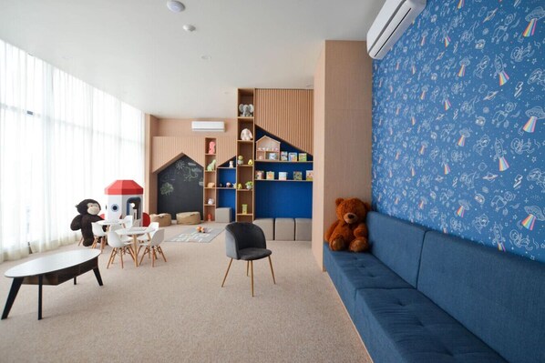 A children's play area with a blue sofa, a teddy bear, and a playhouse.