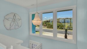 A room with a large window, a chandelier, and a wall decoration.