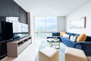 A modern living room with a large TV, blue sofa, and a city view.