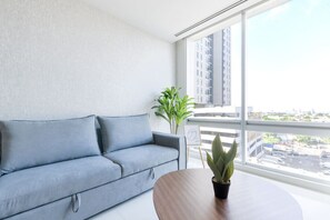 A modern living room with a grey sofa, a small round wooden table, and a potted plant. - ¡Luxury in Santa Lucía! 4ppl | 1 King & Sofa Bed (Monterrey)