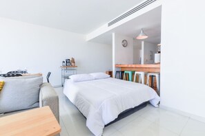 Ett modernt hotellrum med en säng, en liten sittgrupp, ett litet kök och ett matbord.