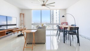 A modern living room with a TV, wooden furniture, a ceiling fan, and a dining area with chairs and a table. - ¡A pasos de Santa Lucía! 1 King & 2 Queen Bed 7Ppl (Monterrey)