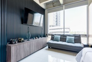 A modern living room with a large TV, a sofa, and a console table with decorative items. - ¡Loft in Santa Lucía! 3 guests, GYM, Pool, Parking (Monterrey)