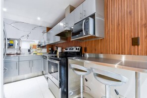 A modern kitchen with stainless steel appliances, wooden paneling, and bar stools. - ¡New in Santa Lucía! 6 guests, GYM, Pool, Parking (Monterrey)