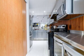 A modern kitchen with stainless steel appliances, wooden paneling, and a tiled floor. - ¡New in Santa Lucía! 6 guests, GYM, Pool, Parking (Monterrey)