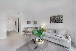 A modern living room with a sofa, coffee table, and a framed cityscape picture on the wall. - Upscale 1BD Condo in Miami- City Views (Miami)
