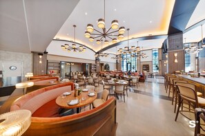 A spacious hotel lobby with multiple seating areas, including booths and tables, and a large chandelier. - Upscale 1BD Condo in Miami- City Views (Miami)
