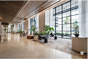 A spacious lobby with large windows, modern furniture, and potted plants. - Upscale 1BD Condo in Miami- City Views (Miami)