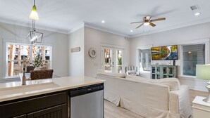 Een moderne keuken met een vaatwasser, een eethoek met een bank en een woonkamer met een televisie en een schilderij.
