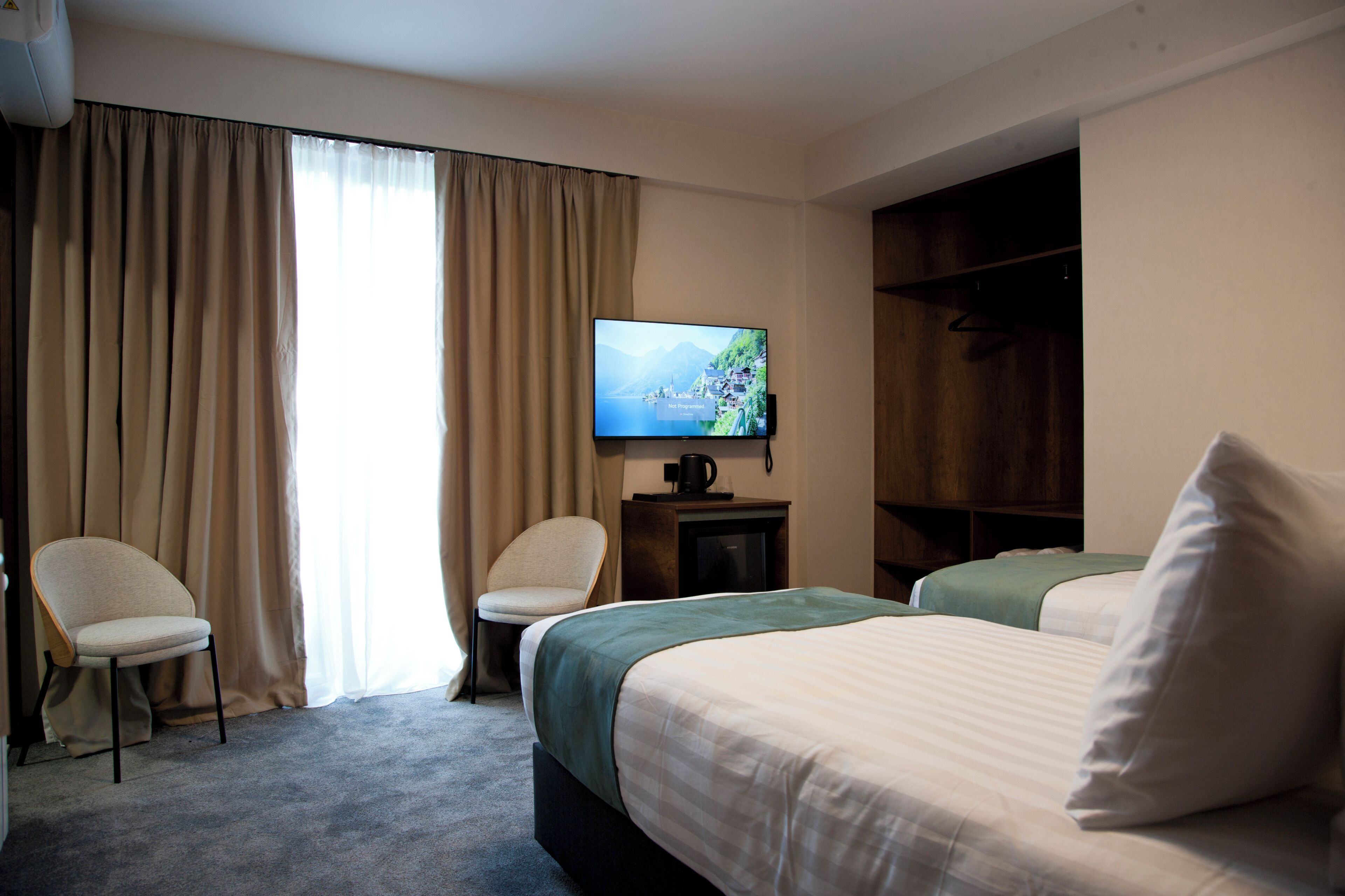 Een hotelkamer met een bed, een stoel, een televisie en een kledingkast.