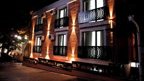 Um edifício de vários andares com varandas, janelas e fachada de tijolos à noite.