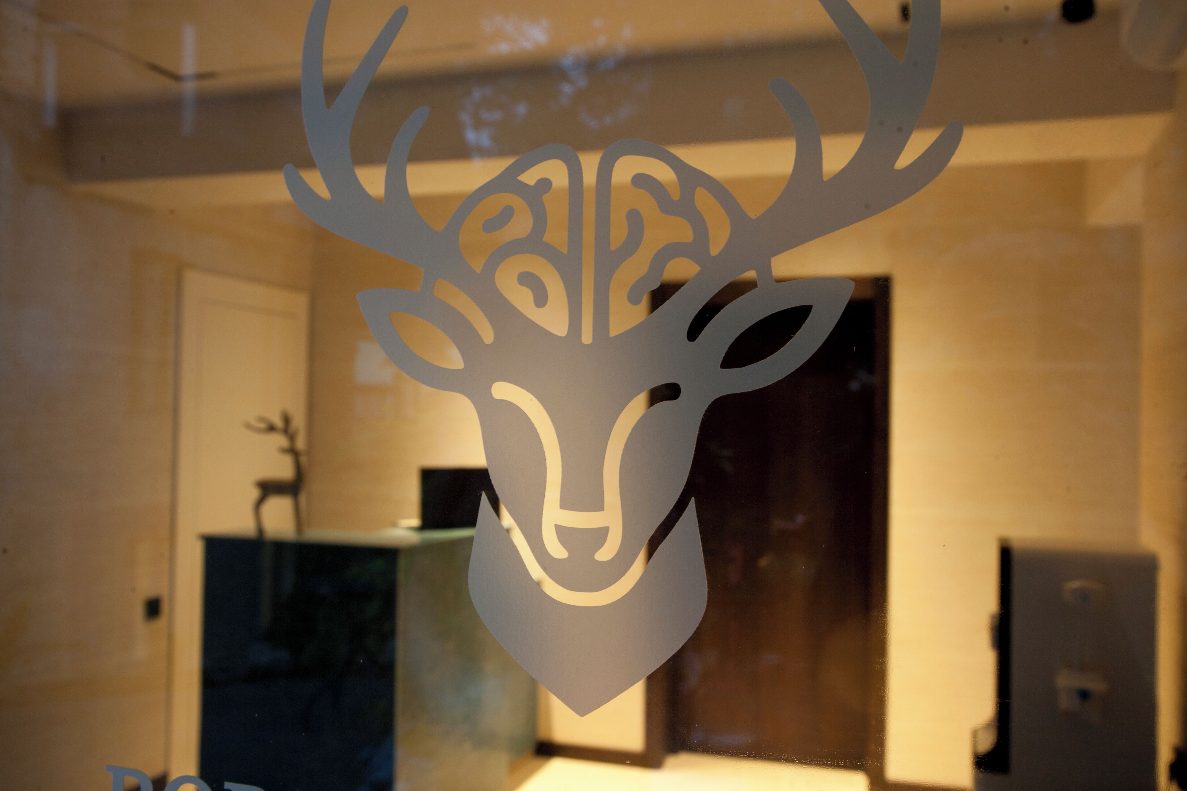 A decorative deer head cutout on a glass window.
