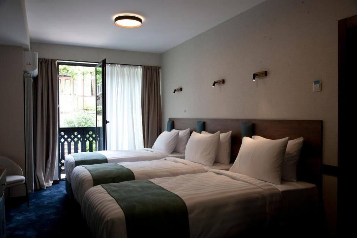 Habitación de hotel con dos camas, un balcón y vistas al exterior.