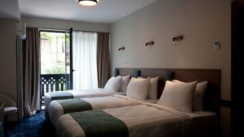 Quarto de hotel com duas camas, varanda e vista para o exterior.