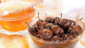 A bowl of chocolate-covered cherries with a honey dipper and a glass of honey.