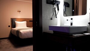 Quarto de hotel com cama, espelho, secador de cabelo e pia.
