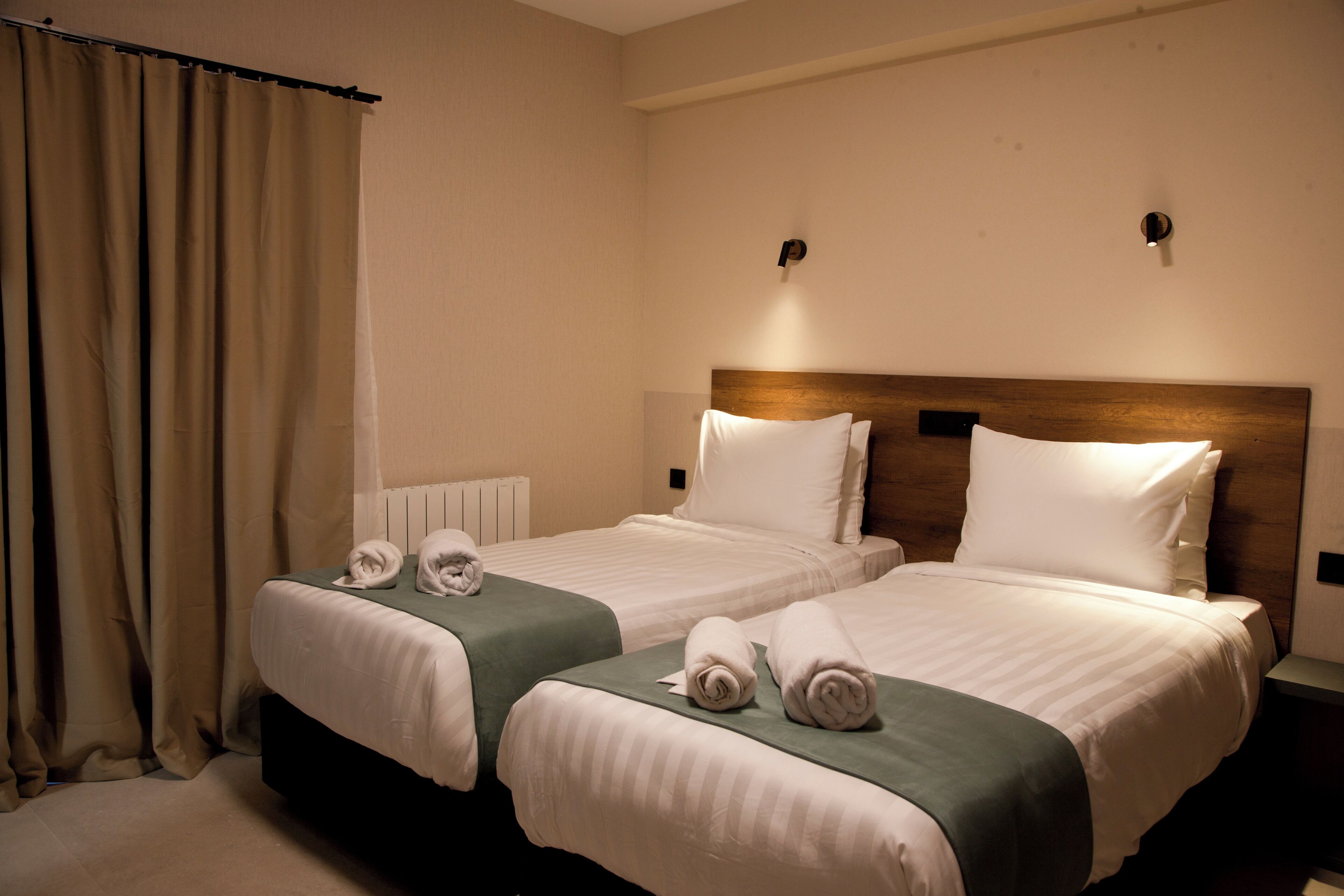 Habitació d'hotel amb dos llits, cadascun amb estores verdes, roba de llit blanca i tovalloles.
