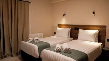Habitació d'hotel amb dos llits, cadascun amb estores verdes, roba de llit blanca i tovalloles.