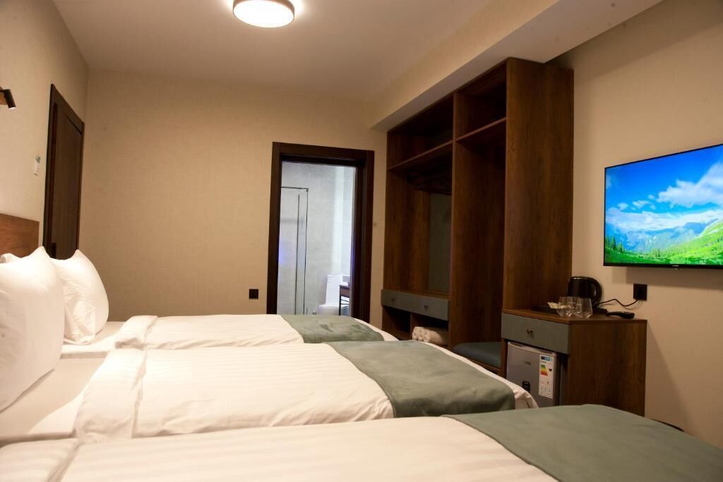 Une chambre d’hôtel avec deux lits, une télévision, une armoire et une porte donnant sur un balcon.