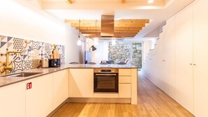 Een moderne keuken met een centraal eiland, een inbouwoven en een stenen wand.