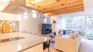 Een moderne keuken met een centraal eiland, een zithoek met stoelen, een bank en een televisie in de woonkamer.