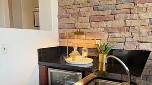 A kitchen with a stone wall, a black countertop, a sink, and a built-in dishwasher. - Spacious 4bedroom villa in tranquil La Quinta, private gated lake community (La Quinta)