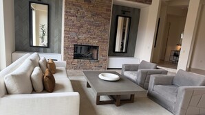 A modern living room with a stone fireplace, a sofa, a coffee table, and two armchairs. - Spacious 4bedroom villa in tranquil La Quinta, private gated lake community (La Quinta)