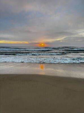 Une plage avec des vagues et un coucher de soleil.