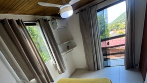 A bedroom with a bed, a ceiling fan, an air conditioning unit, and a view of the outdoors. - Pousada Mahara (Imbituba)