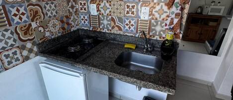 A compact kitchen with a gas stove, sink, and a small refrigerator.
