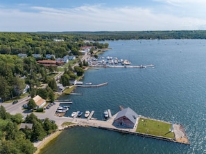 An aerial view of a lakeside town with a marina, docked boats, and residential buildings.