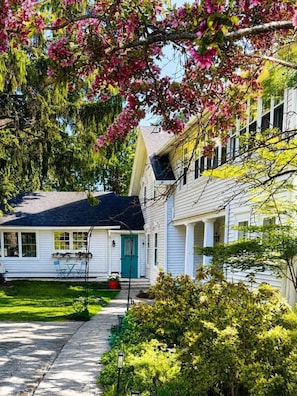 A two-story house with a front porch, a green door, and a visible garage door.