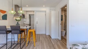 Una cucina moderna con un'area bar, una porta bianca e un bagno a vista.